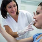 Medic estetician care examinează fața unei paciente în timpul unei consultații estetice